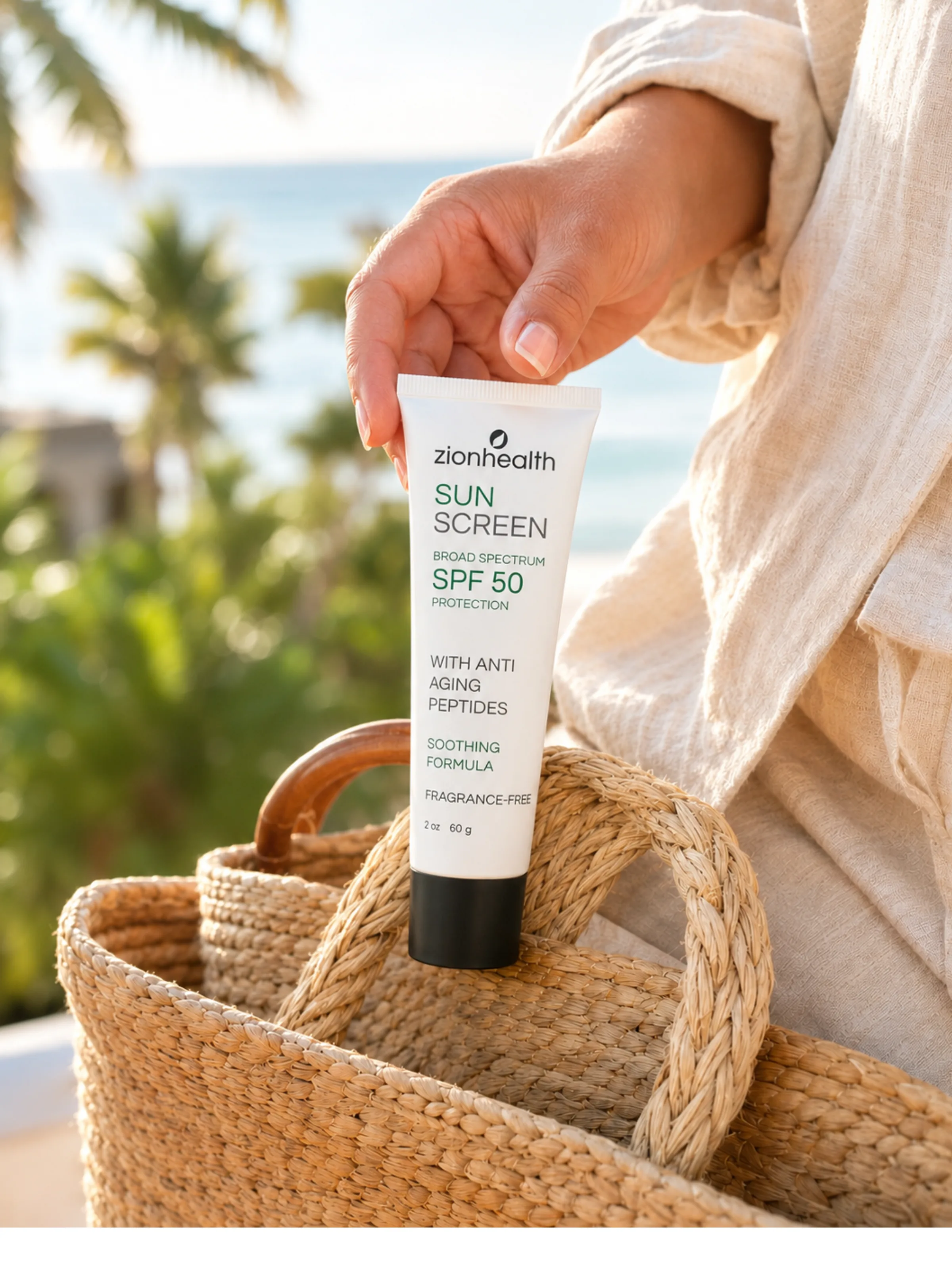 A hand pulling a tube of Zion Health Sunscreen SPF 50 from a woven beach bag, with palm trees and ocean in the background.
