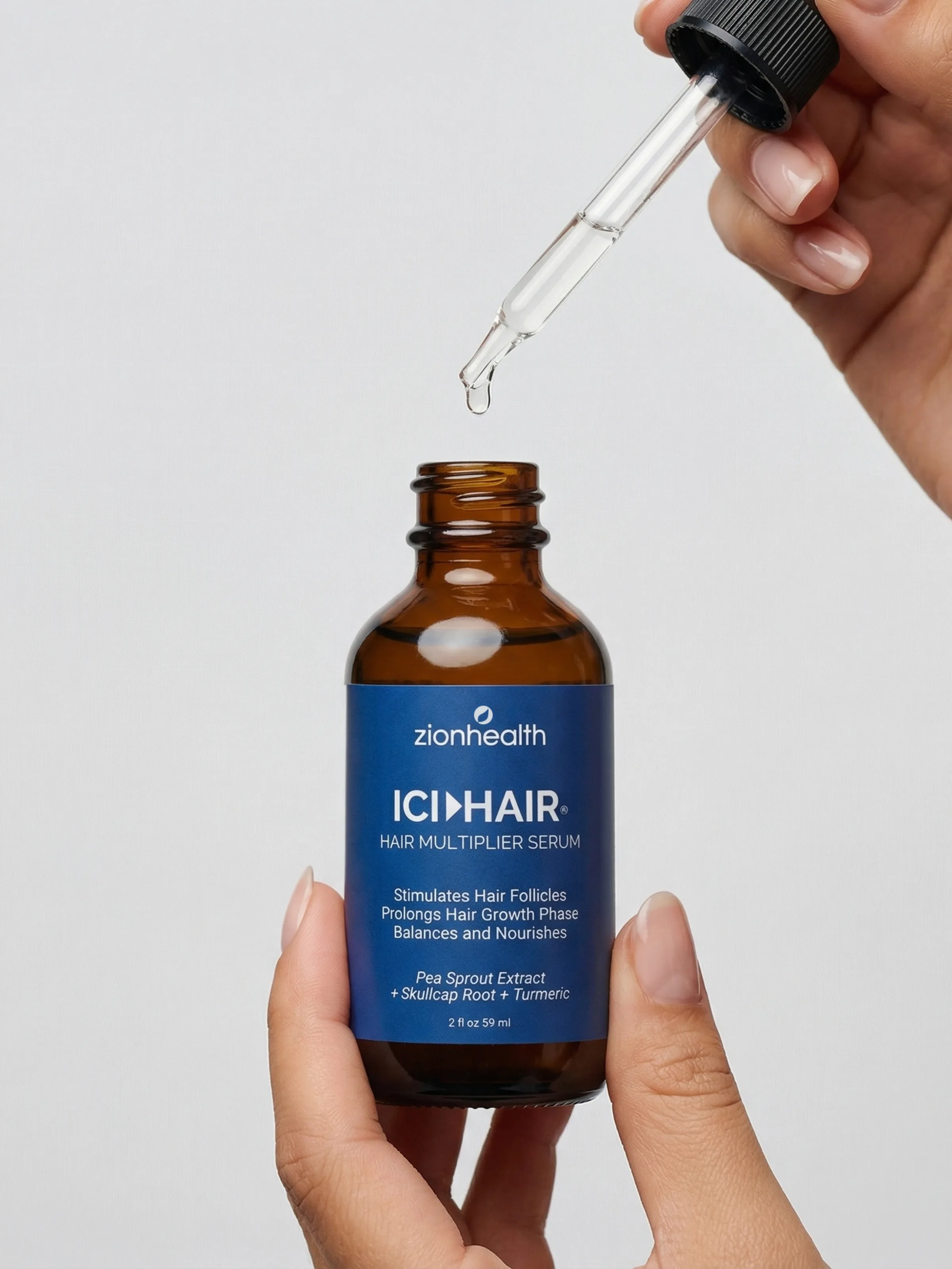 A dropper bottle of Zion Health ICI Hair Multiplier Serum with the glass dropper resting beside it.